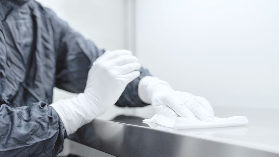 specialist-cleaning-protective-uniform-close-up Specialist cleaner wearing protective uniform and gloves wiping a surface